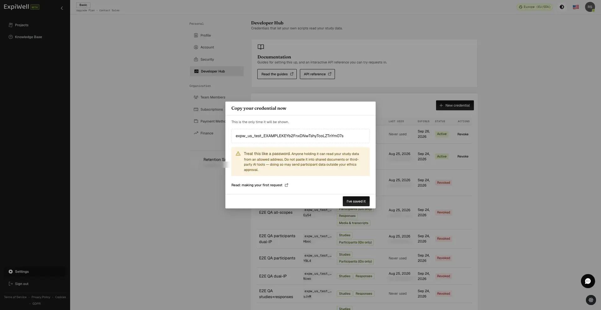 The one-time reveal dialog showing an example credential with a Copy button, a warning to treat it like a password, and a link to the first-request guide